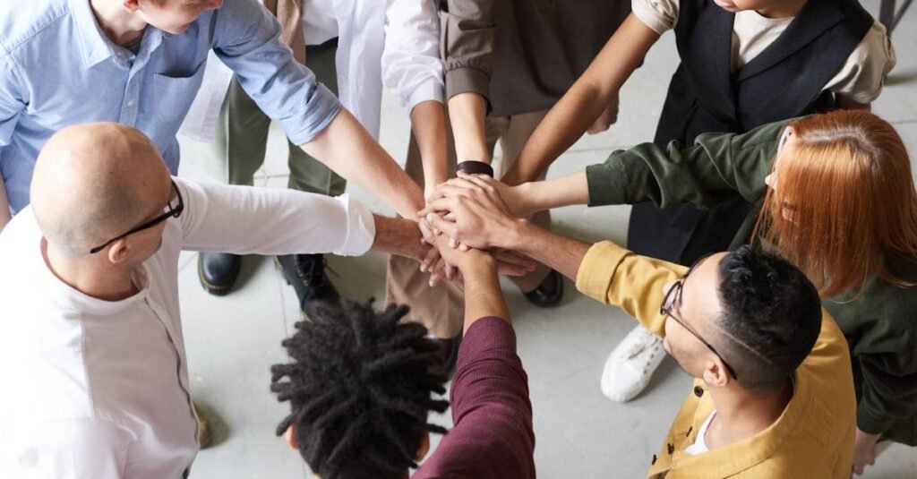 pexels-photo-3184423-3184423-1 A diverse group of professionals joins hands in a team-building exercise indoors.
